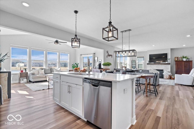 kitchen with a sink, open floor plan, white cabinetry, a fireplace, and dishwasher