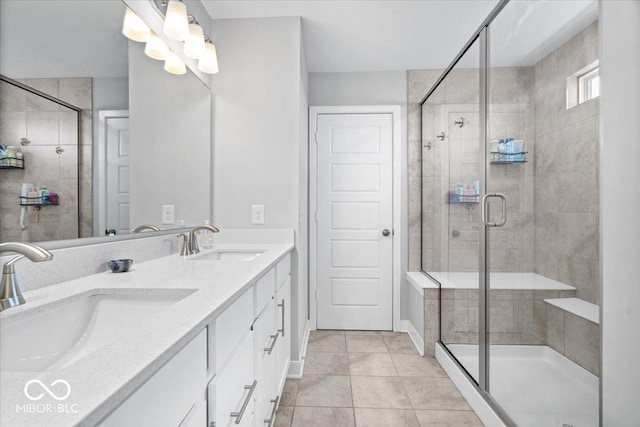 bathroom featuring tile patterned flooring, double vanity, a stall shower, and a sink