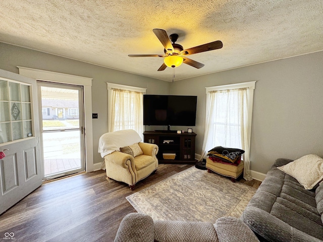 living area featuring baseboards, a textured ceiling, wood finished floors, and a ceiling fan