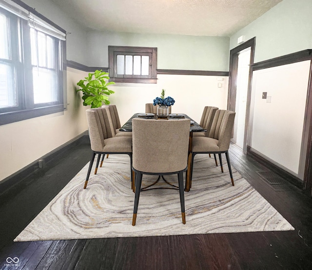 dining area with wood finished floors, baseboards, and a textured ceiling