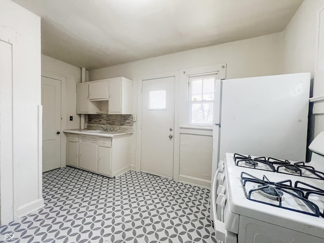 kitchen featuring light floors, light countertops, decorative backsplash, white appliances, and a sink