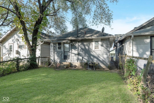 rear view of house with a yard and fence