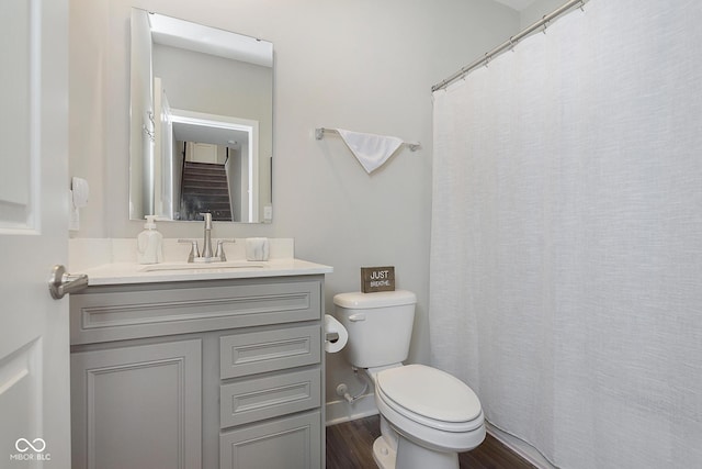 bathroom with curtained shower, baseboards, toilet, wood finished floors, and vanity