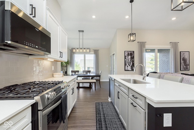 kitchen with dark wood-style flooring, a sink, decorative backsplash, light countertops, and appliances with stainless steel finishes