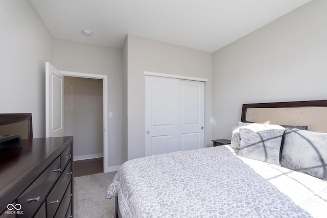 carpeted bedroom featuring a closet and baseboards