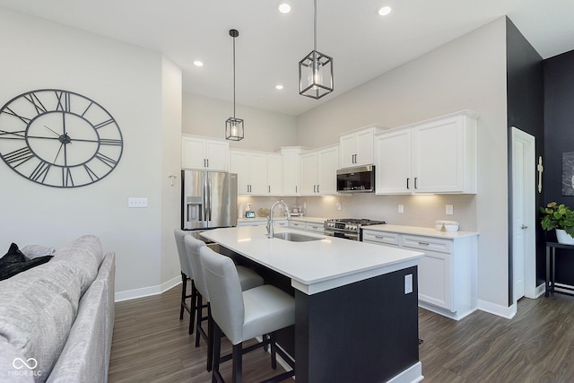 kitchen featuring white cabinetry, dark wood-style flooring, a sink, appliances with stainless steel finishes, and a kitchen bar