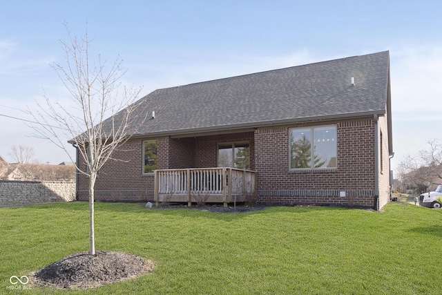 back of property featuring brick siding, a deck, a shingled roof, and a yard