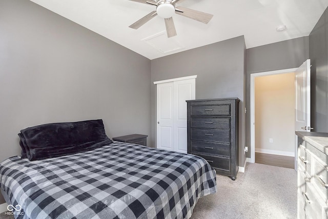 bedroom with ceiling fan, baseboards, light colored carpet, attic access, and a closet