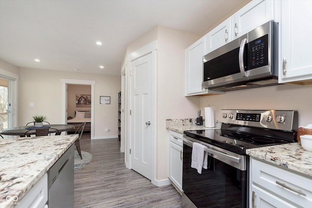 kitchen with baseboards, light wood-style flooring, recessed lighting, stainless steel appliances, and white cabinets