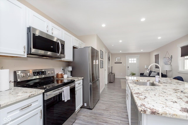 kitchen featuring light stone countertops, recessed lighting, appliances with stainless steel finishes, white cabinetry, and a sink