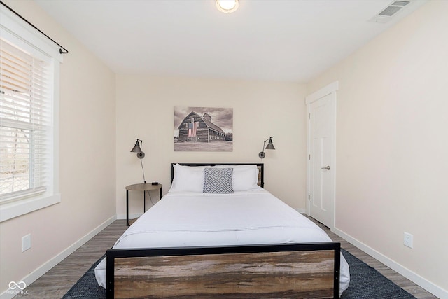 bedroom with visible vents, baseboards, and wood finished floors