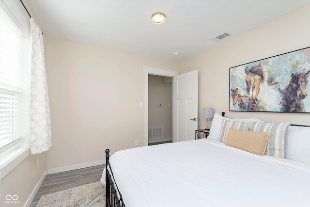 bedroom featuring wood finished floors, baseboards, and visible vents