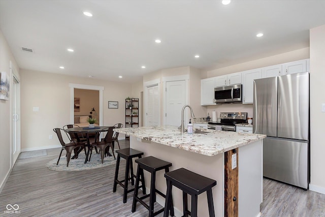 kitchen with a center island with sink, visible vents, recessed lighting, a sink, and appliances with stainless steel finishes