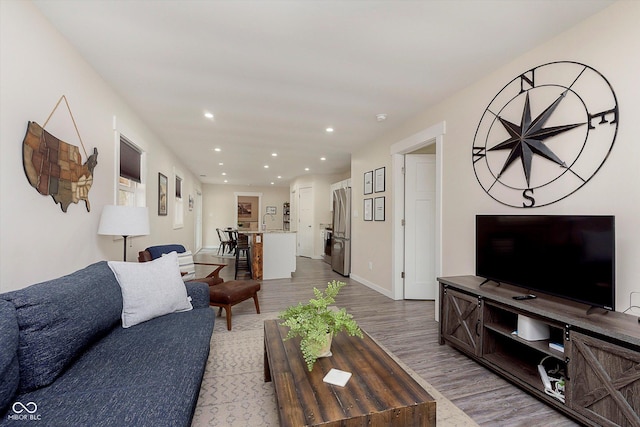 living room featuring recessed lighting, baseboards, and light wood-style floors