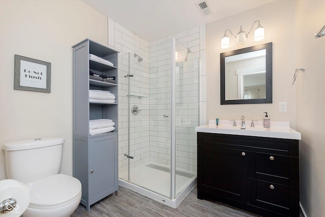 bathroom featuring vanity, wood finished floors, visible vents, a shower stall, and toilet