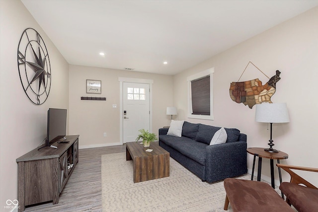 living room featuring light wood finished floors, visible vents, recessed lighting, and baseboards