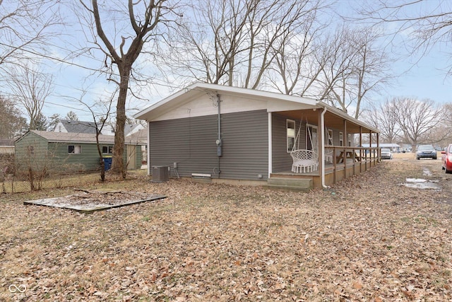 view of side of property featuring cooling unit and covered porch