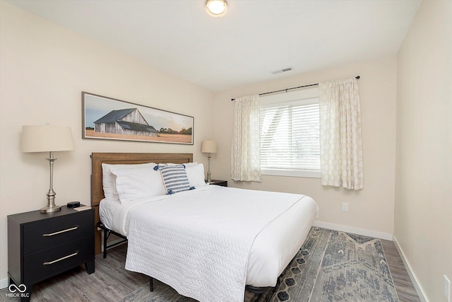 bedroom featuring visible vents, baseboards, and wood finished floors