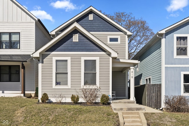 view of front of house with board and batten siding, a front lawn, and fence