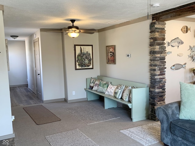 interior space featuring a ceiling fan, baseboards, visible vents, beam ceiling, and a textured ceiling