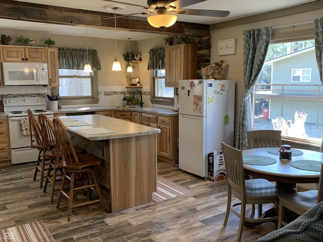 kitchen featuring a sink, a wealth of natural light, white appliances, and wood finished floors