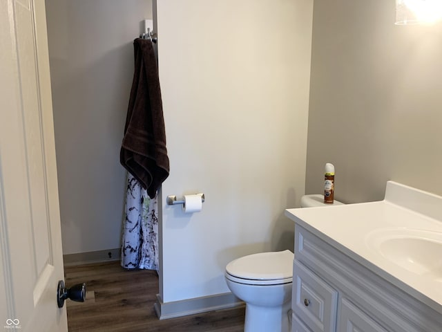 bathroom featuring toilet, vanity, baseboards, and wood finished floors