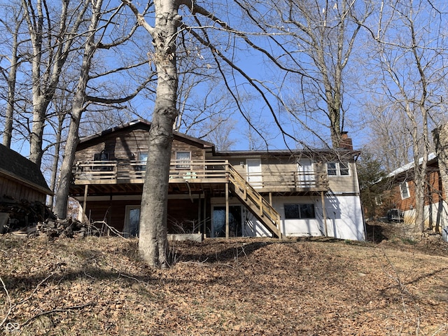 back of house featuring stairs, a deck, and a chimney