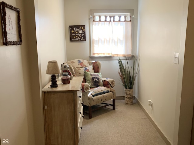 sitting room with baseboards and light colored carpet