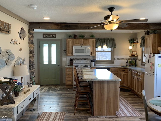 kitchen featuring white appliances, dark wood-style floors, a sink, a textured ceiling, and a kitchen bar