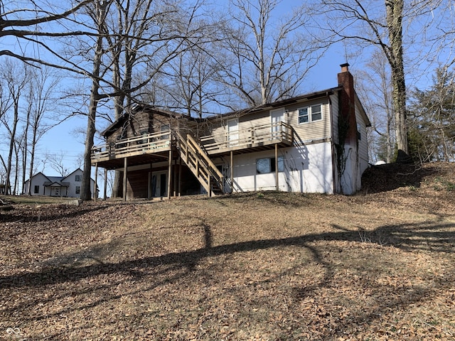 rear view of property featuring stairway, a deck, and a chimney