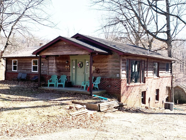 view of front of house with cooling unit, brick siding, and a porch