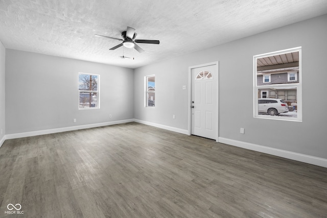 interior space with baseboards, a textured ceiling, wood finished floors, and a ceiling fan