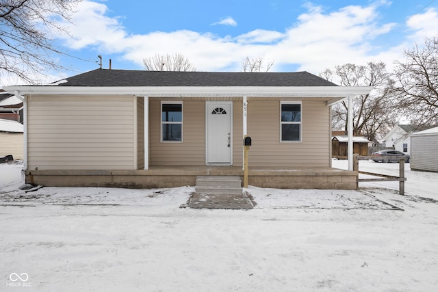 bungalow with covered porch and a shingled roof