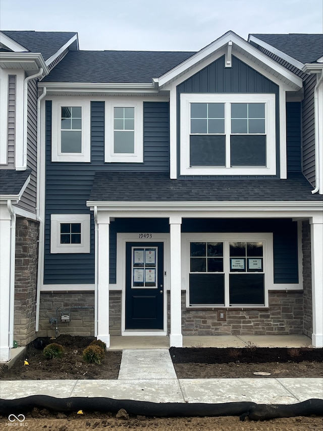 view of front of home with stone siding, board and batten siding, and roof with shingles