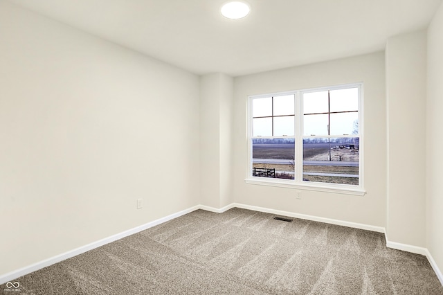 unfurnished room featuring carpet, visible vents, and baseboards