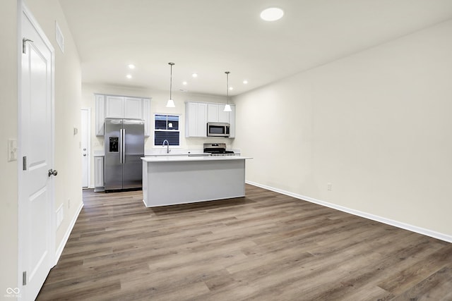 kitchen with a kitchen island, recessed lighting, stainless steel appliances, dark wood-type flooring, and light countertops