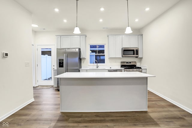 kitchen with a kitchen island, light countertops, appliances with stainless steel finishes, dark wood-style floors, and a sink