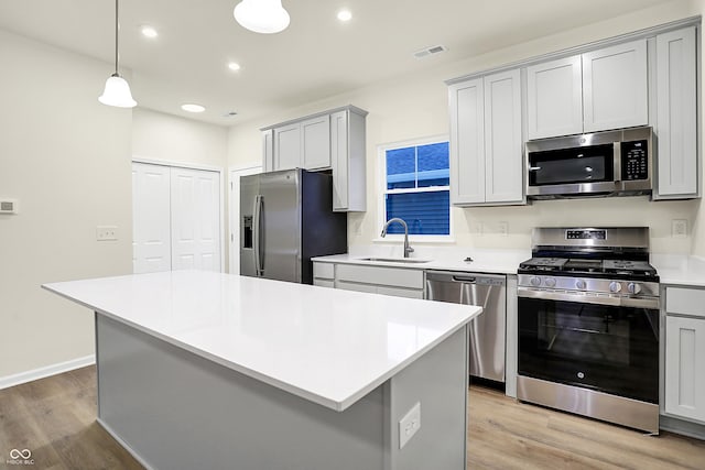 kitchen with light countertops, light wood finished floors, appliances with stainless steel finishes, and a sink