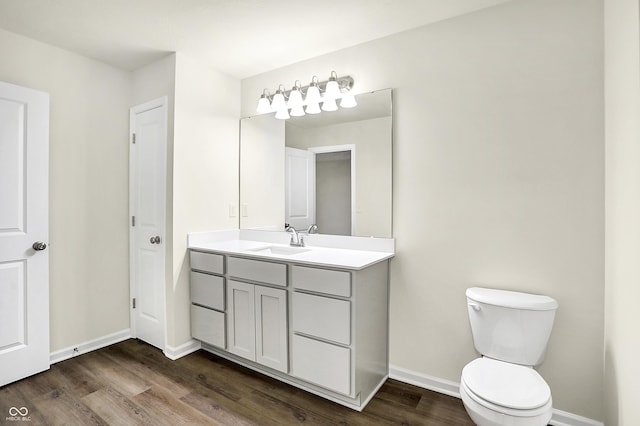 bathroom with baseboards, toilet, wood finished floors, and vanity