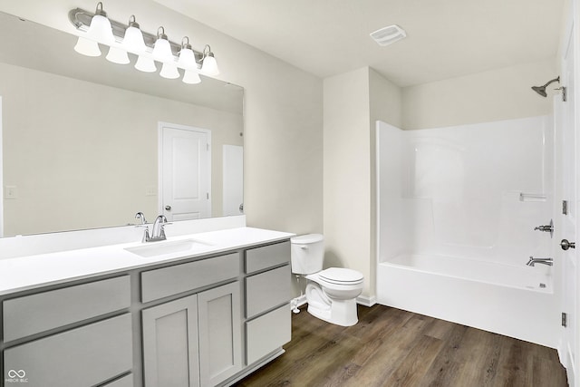 bathroom with visible vents, toilet, wood finished floors, bathing tub / shower combination, and vanity