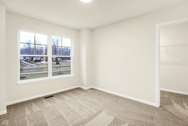 unfurnished bedroom featuring a spacious closet, visible vents, baseboards, and carpet floors