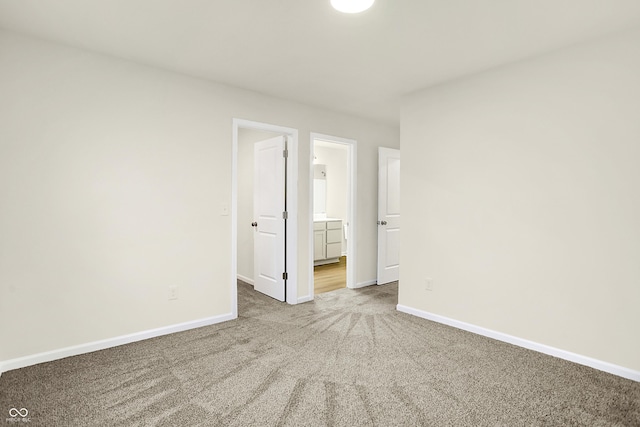 unfurnished bedroom with baseboards, carpet floors, and connected bathroom