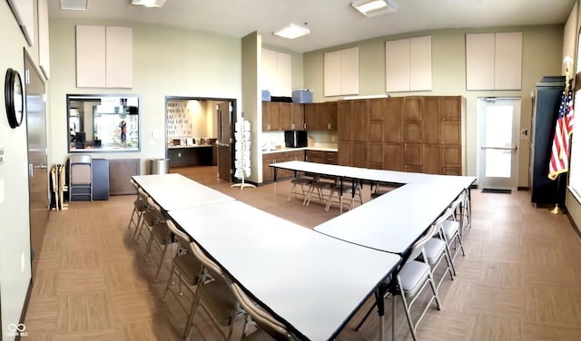 kitchen with a spacious island, brown cabinets, light countertops, and a high ceiling