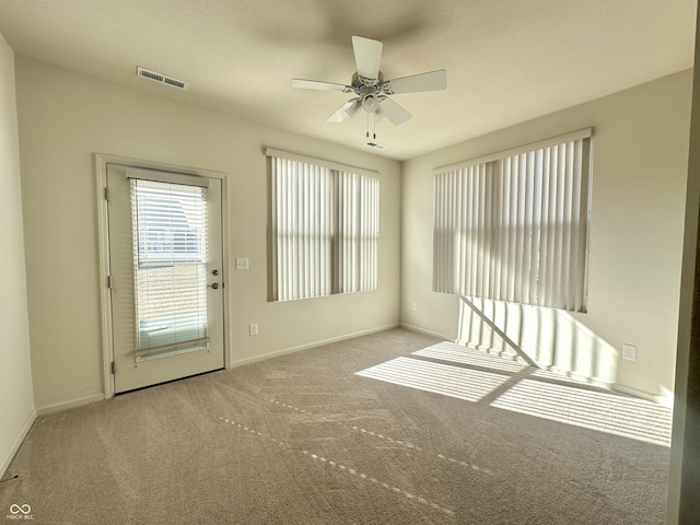 spare room with visible vents, baseboards, ceiling fan, and carpet flooring