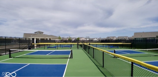 view of tennis court with a residential view and fence