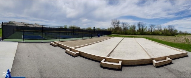 view of property's community with a tennis court and fence