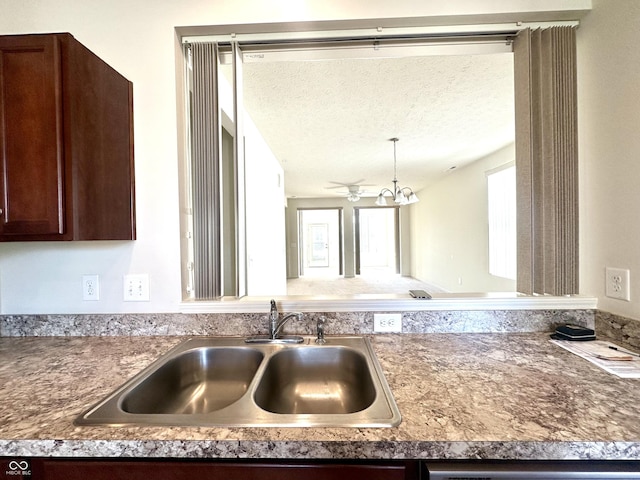 interior details featuring dark brown cabinetry, decorative light fixtures, dishwashing machine, an inviting chandelier, and a sink