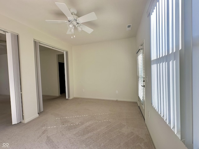 unfurnished bedroom featuring a ceiling fan, light colored carpet, visible vents, and baseboards