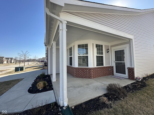 entrance to property featuring covered porch and brick siding