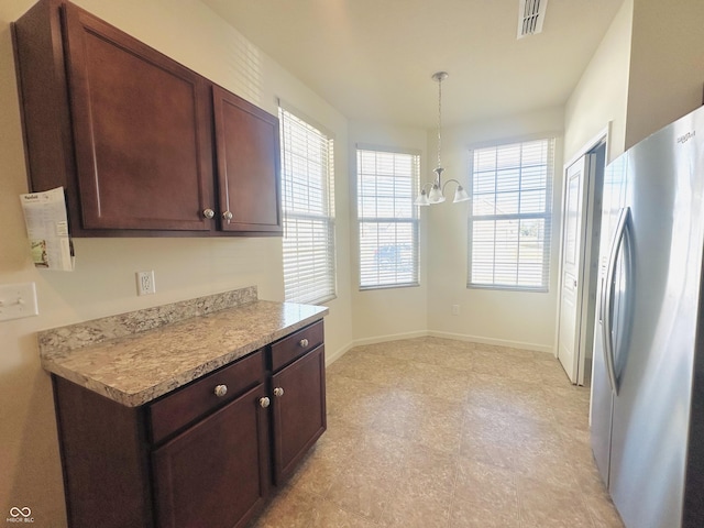 kitchen featuring visible vents, freestanding refrigerator, light countertops, baseboards, and a chandelier